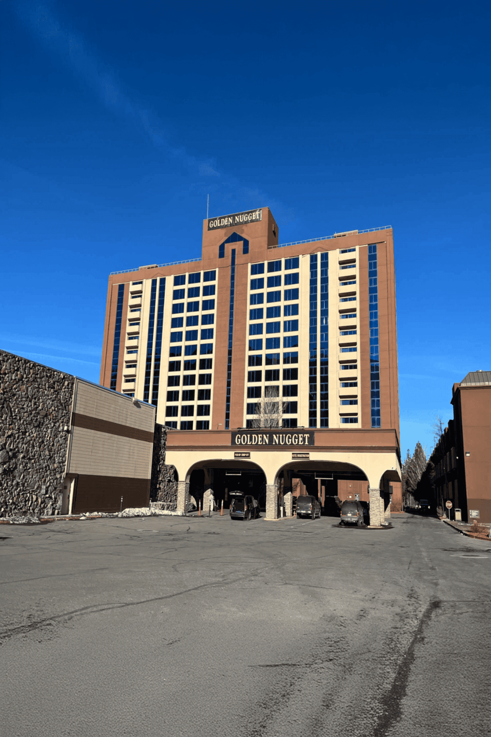 Modern hotel building with "Golden Nugget" signage and parking area, located in an urban area.