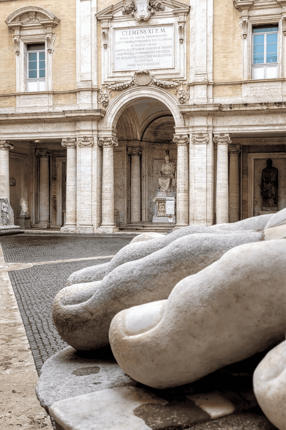 Stone sculptures in front of historic Roman architecture, showcasing ancient sculptures and classical design.