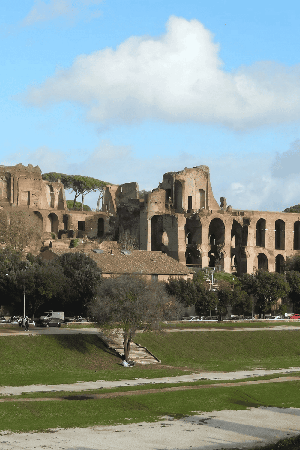 Ancient Roman ruins on a hill with greenery and a bright blue sky, historic site sightseeing in Rome.