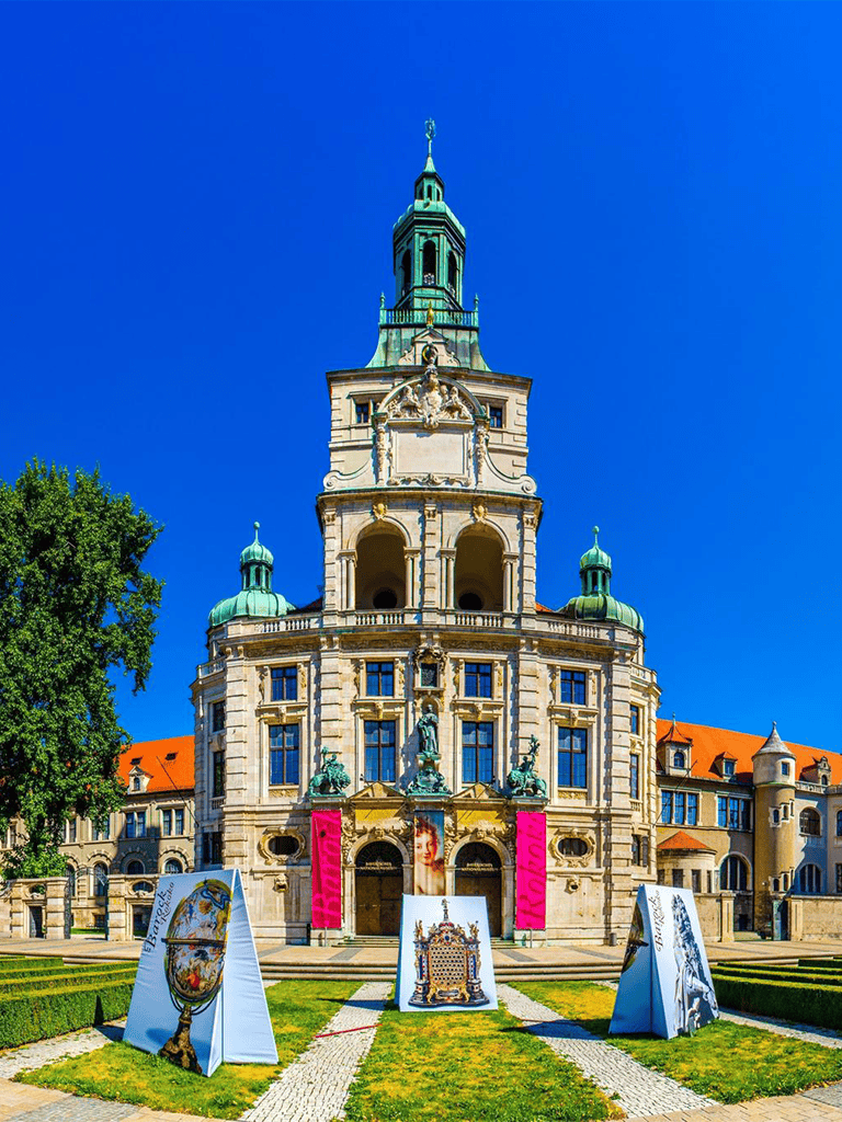 Historic castle with ornate architecture and vibrant art displays in a lush garden setting.