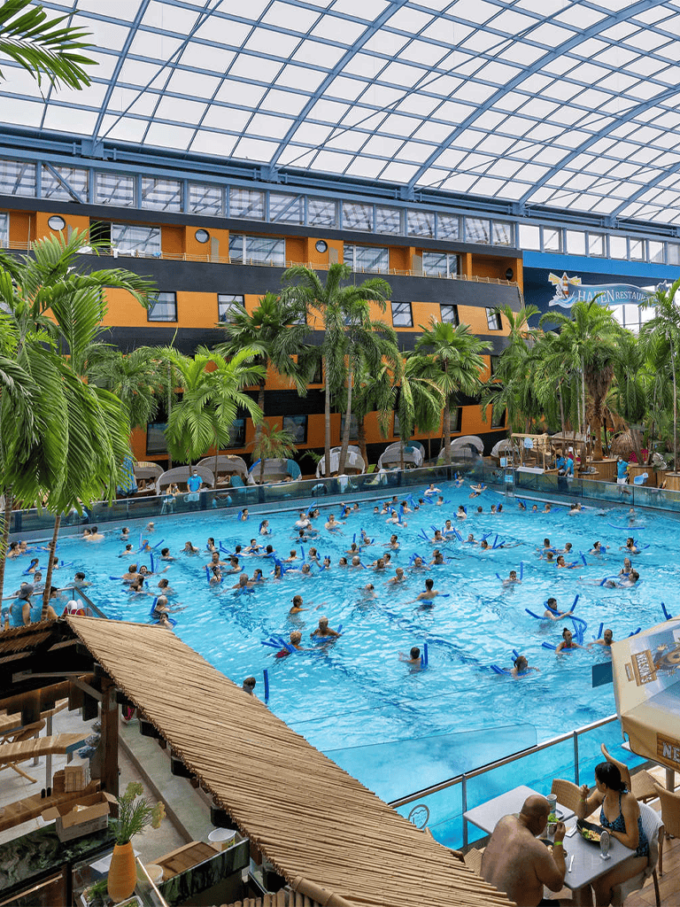 Indoor tropical water park with swimming pools and palm trees at QuestForDirections.