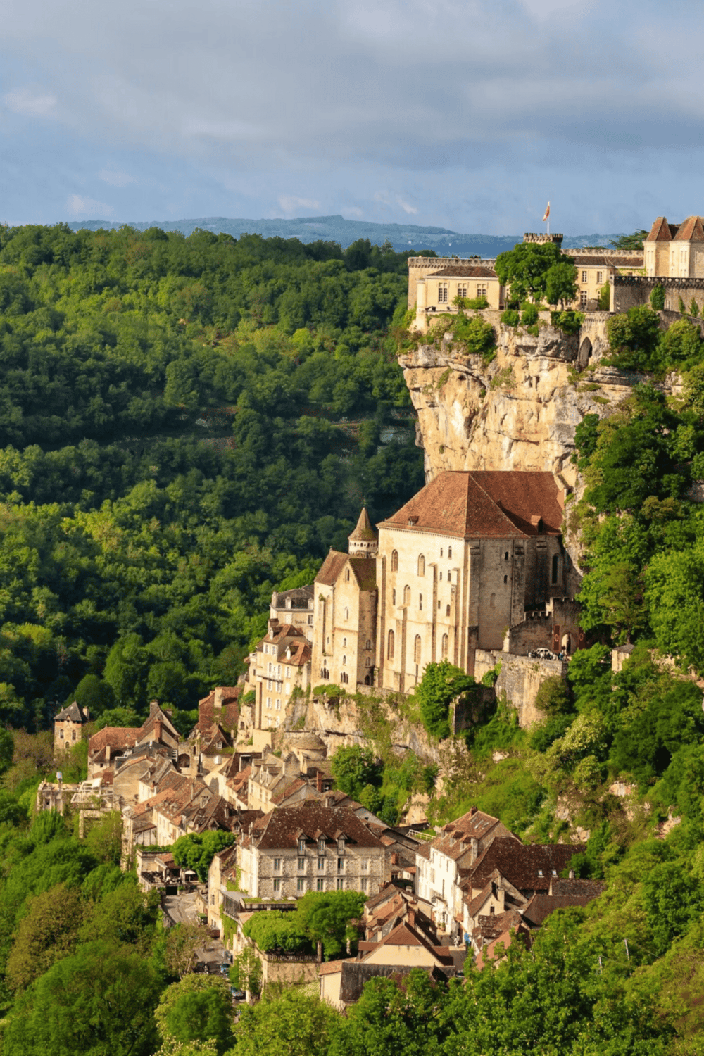 1. Medieval castle on rocky hilltop in lush green landscape, France.