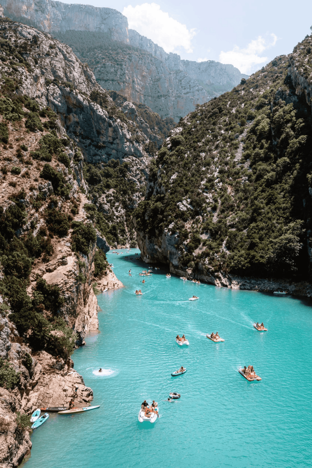 Vibrant turquoise river surrounded by scenic canyon with boats, ideal for outdoor adventures.