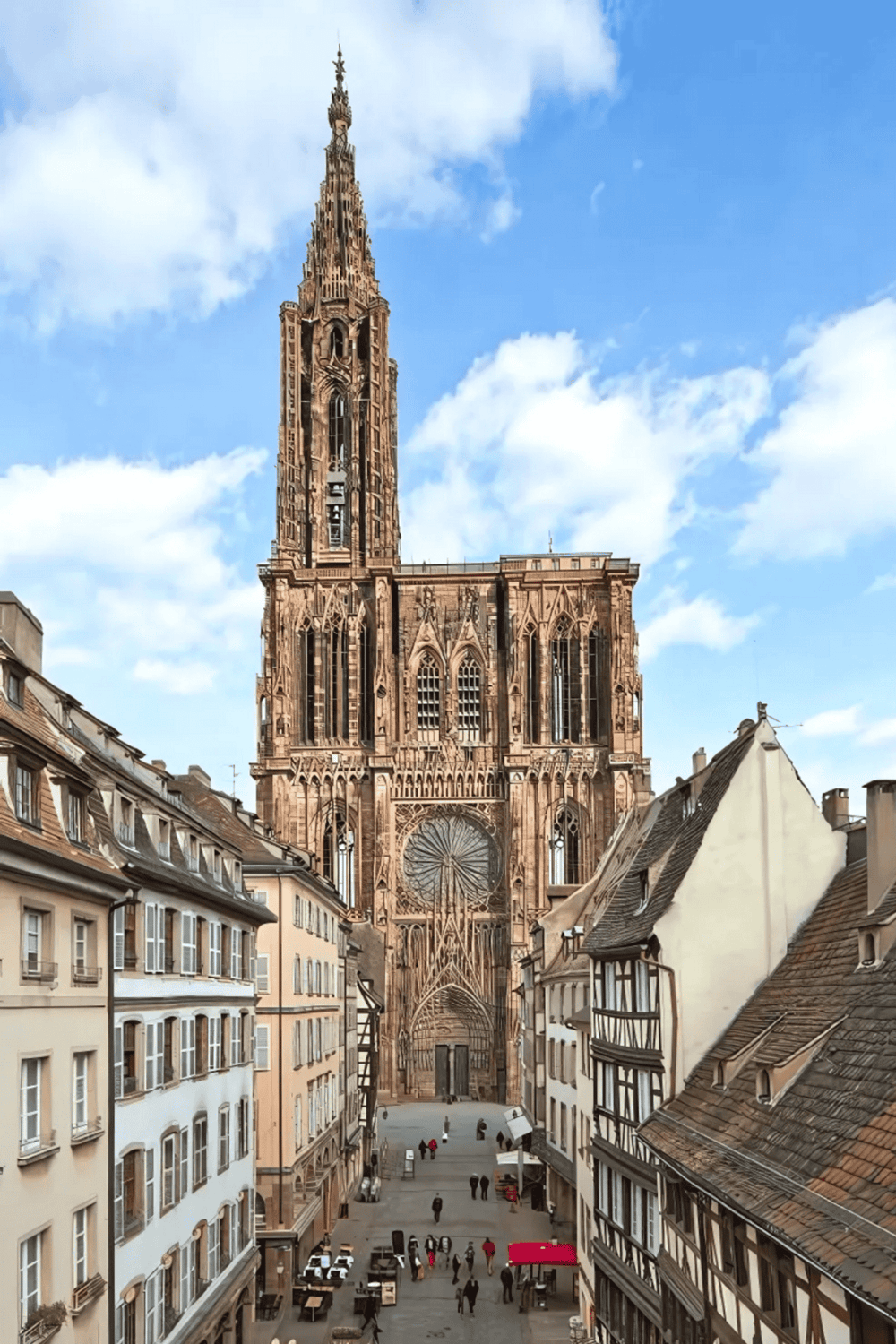 Ornate Gothic cathedral in Strasbourg, France with surrounding historic streets and lively outdoor cafes.
