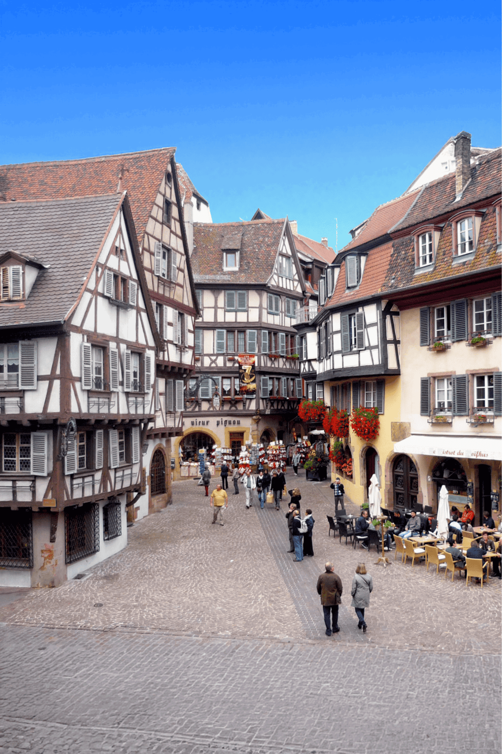 Charming European cobblestone street with half-timbered houses and outdoor cafes.