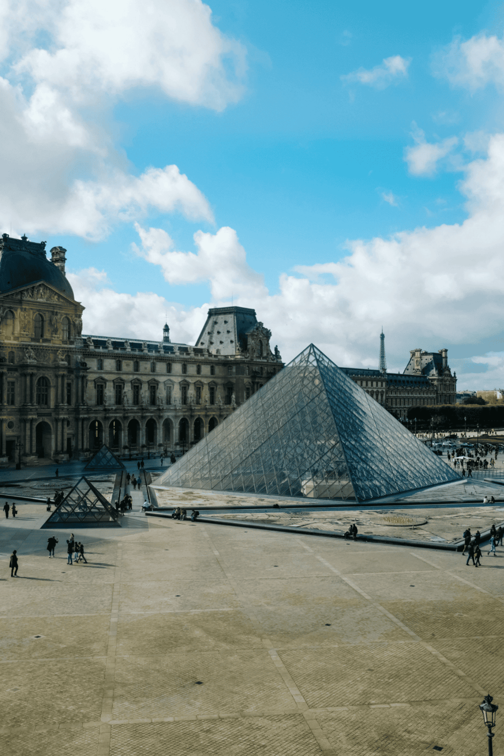 Historic Paris Louvre Museum with glass pyramid entrance and classic architecture, perfect for sightseeing.