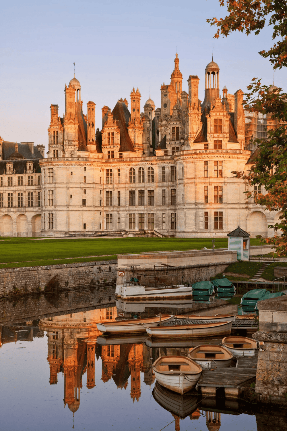 Majestic French castle with reflection in river at sunset, scenic historic landmark in France.