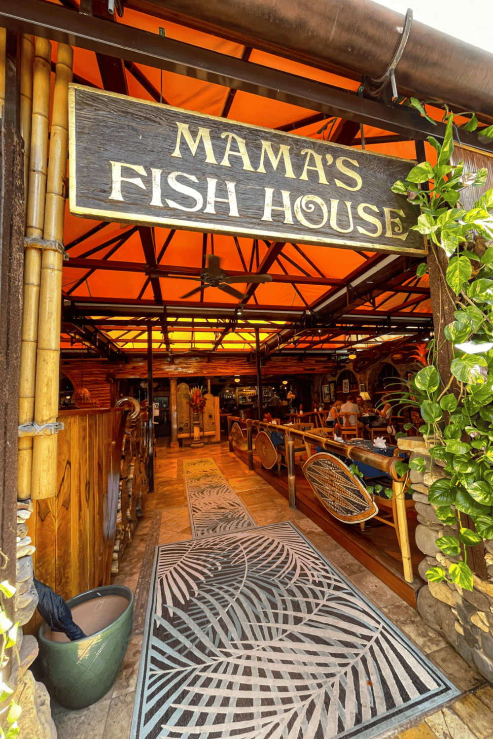 Fresh seafood restaurant entrance with tropical decor and lush green plants.