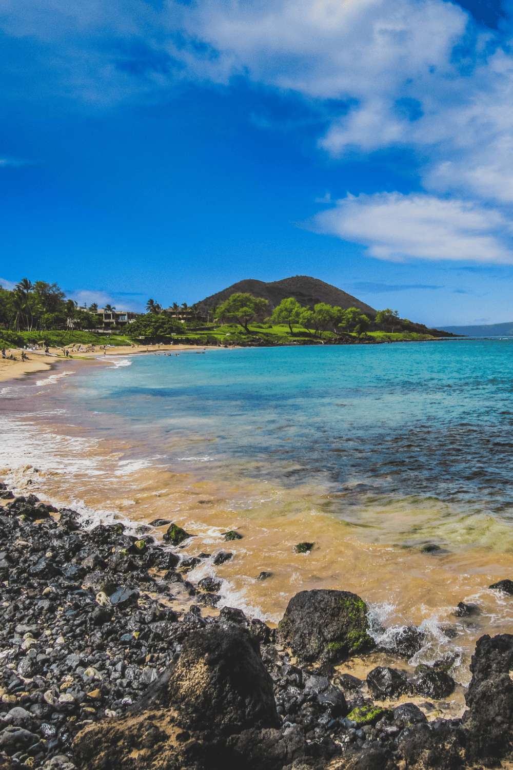 Beautiful tropical beach with clear blue water, lush green trees, and a scenic mountain backdrop. Perfect for relaxation and outdoor adventures.