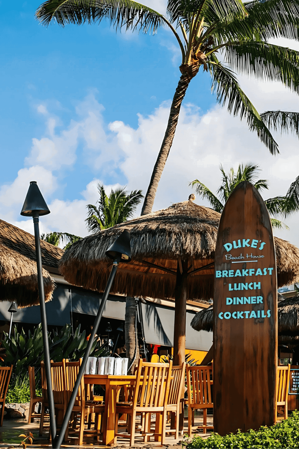 Relaxing beachside restaurant with tiki huts, palm trees, and outdoor dining at Duke's Beach House.