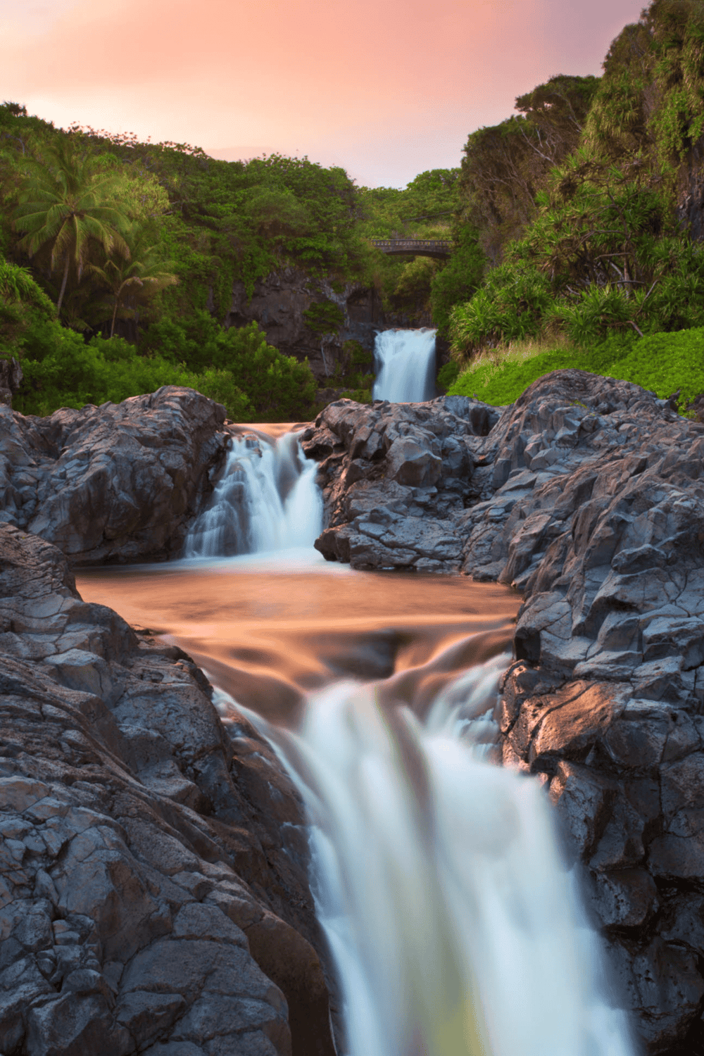 Serene waterfall surrounded by lush tropical greenery at sunset for adventure travel and nature exploration.
