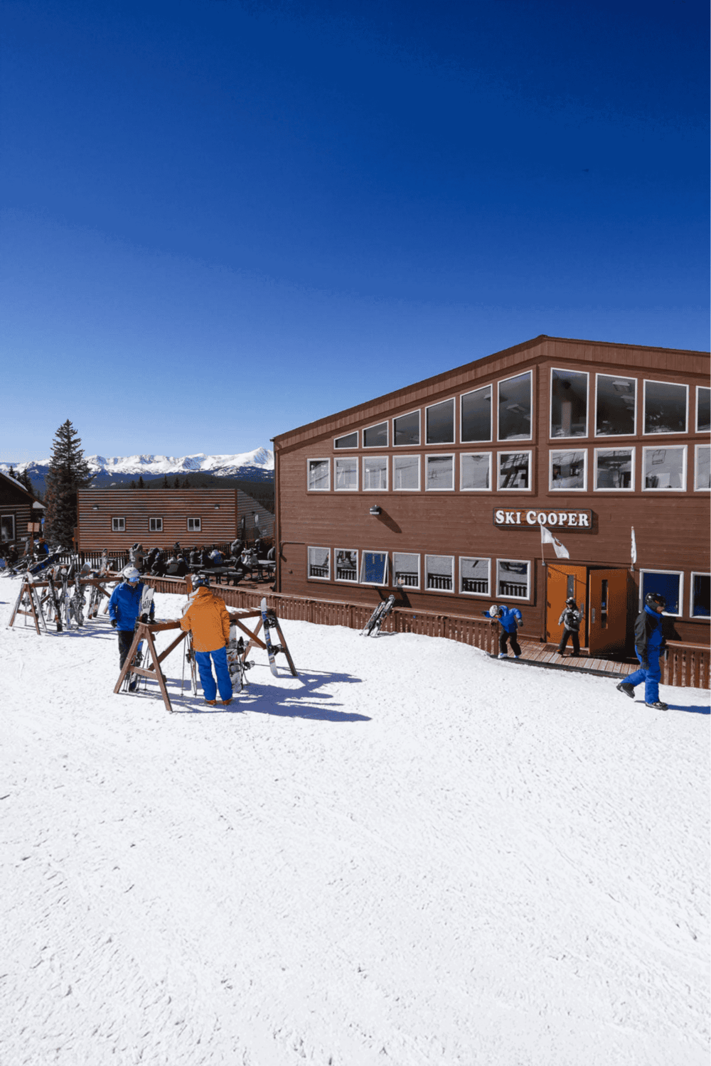 Snowy mountain ski lodge with skiers and snowboarders at ski resort winter outdoor activity.
