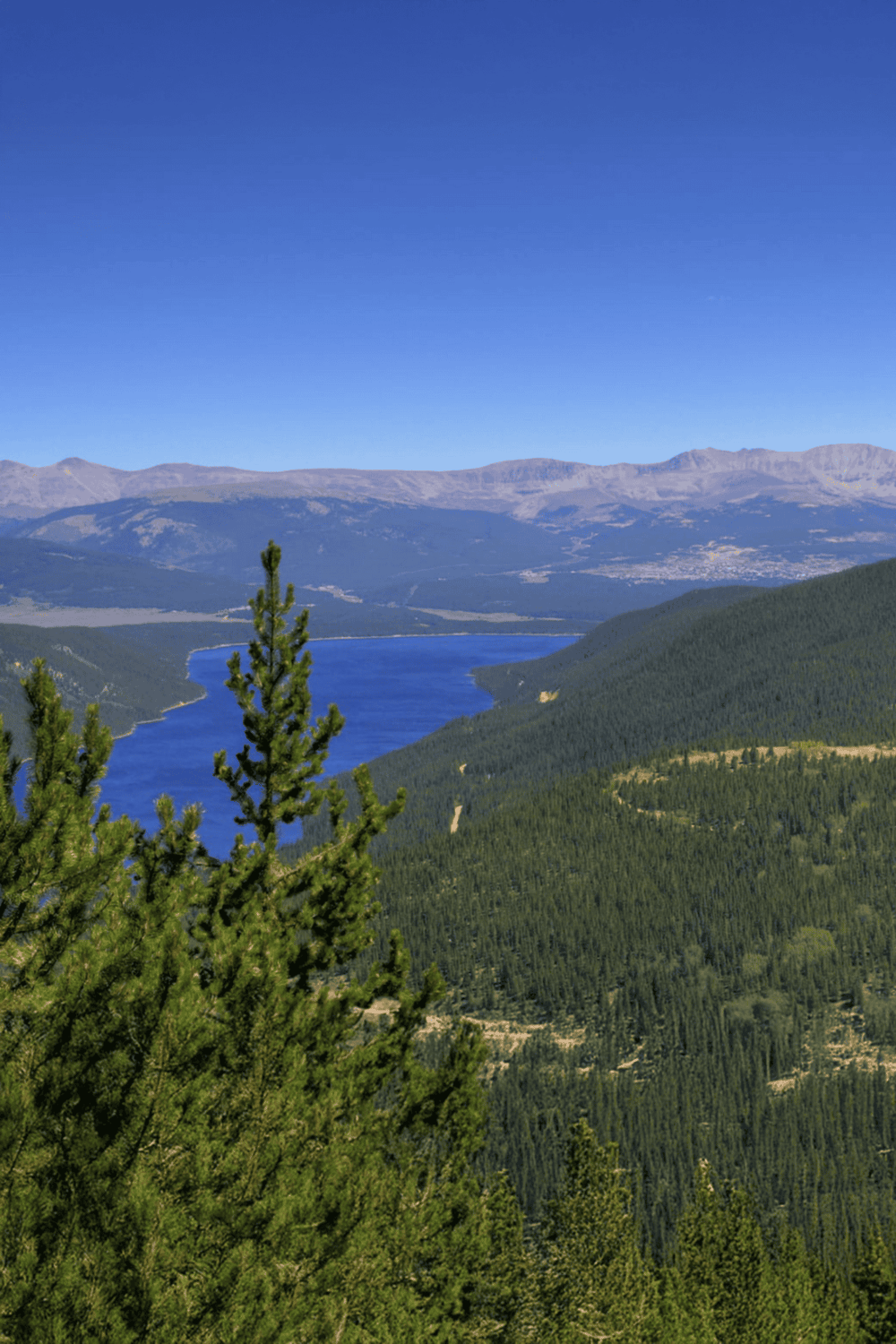 Serene mountain lake with lush green forest surrounding, scenic outdoor adventure destination.