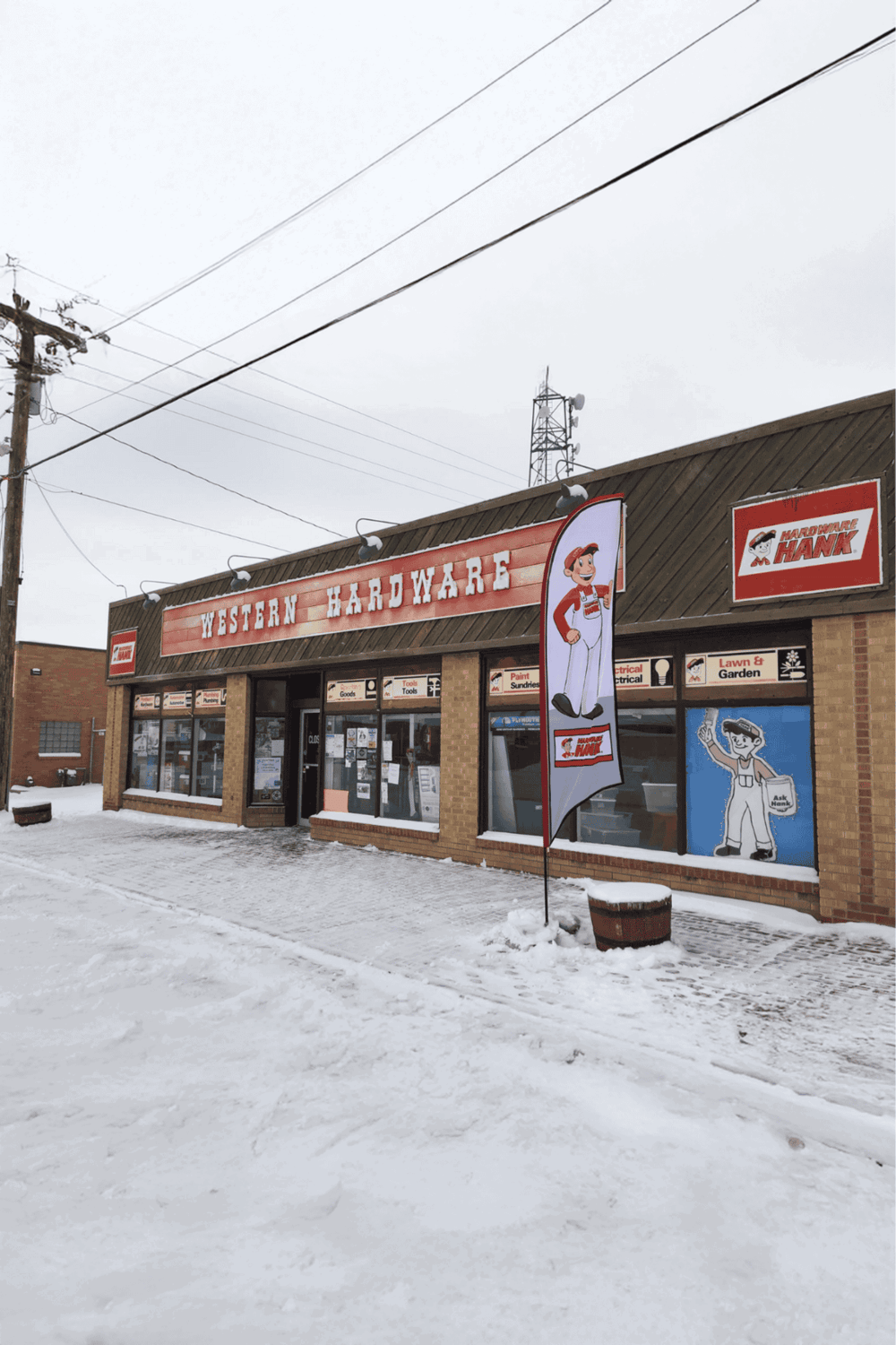 Colorful hardware store storefront with snow-covered street, sign, and cartoon mascot logo.