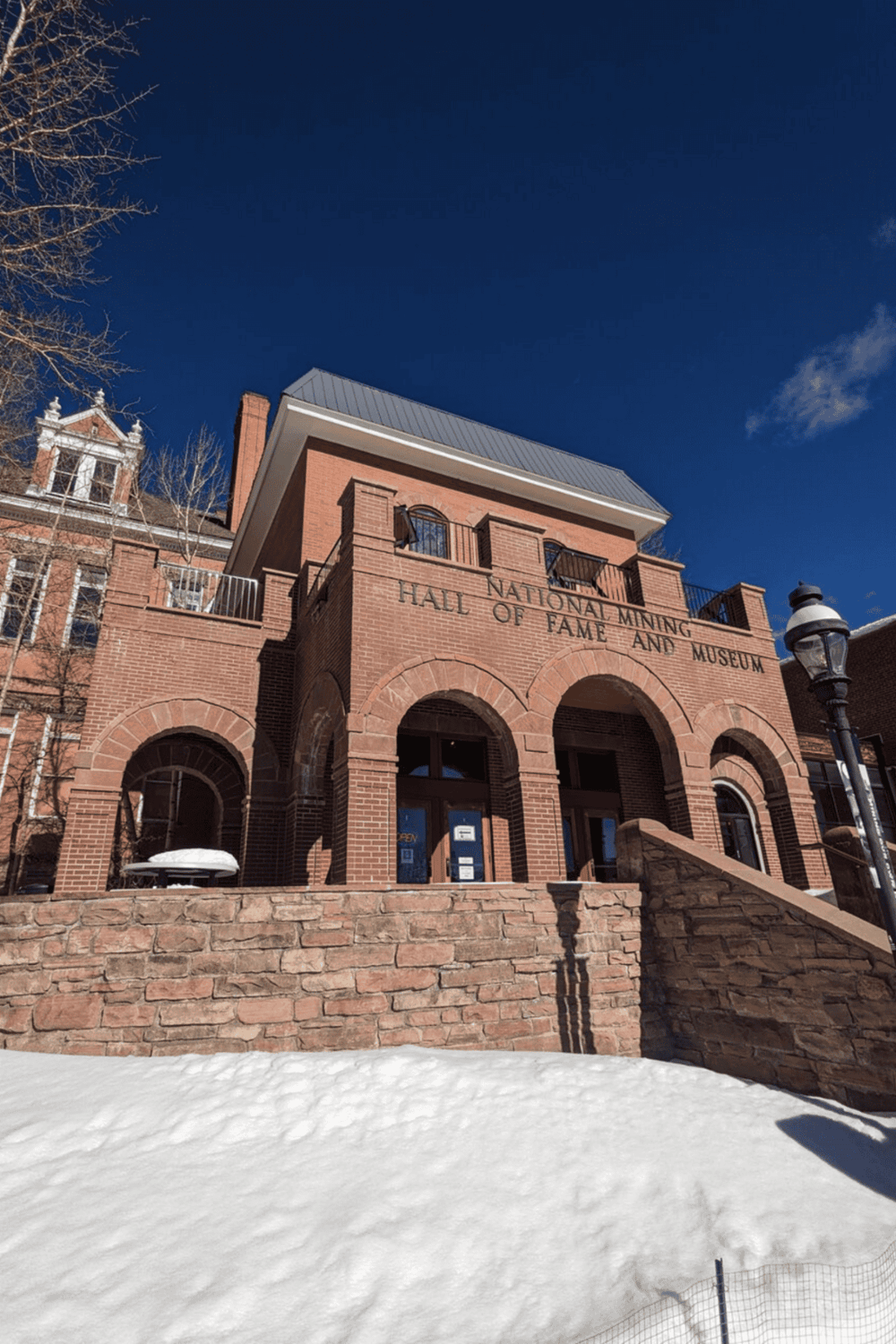 Historic mining museum building in Colorado under clear blue sky, snow-covered ground, and classic brick architecture.