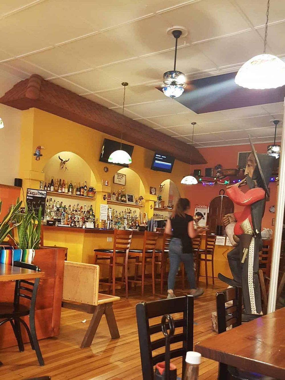Colorful indoor scene at a Mexican restaurant with bar, bartenders, and lively decor, creating a vibrant dining atmosphere.