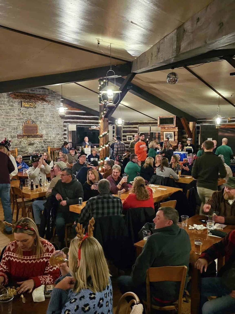 Festive indoor gathering at a cozy rustic restaurant with holiday decorations and joyful patrons.