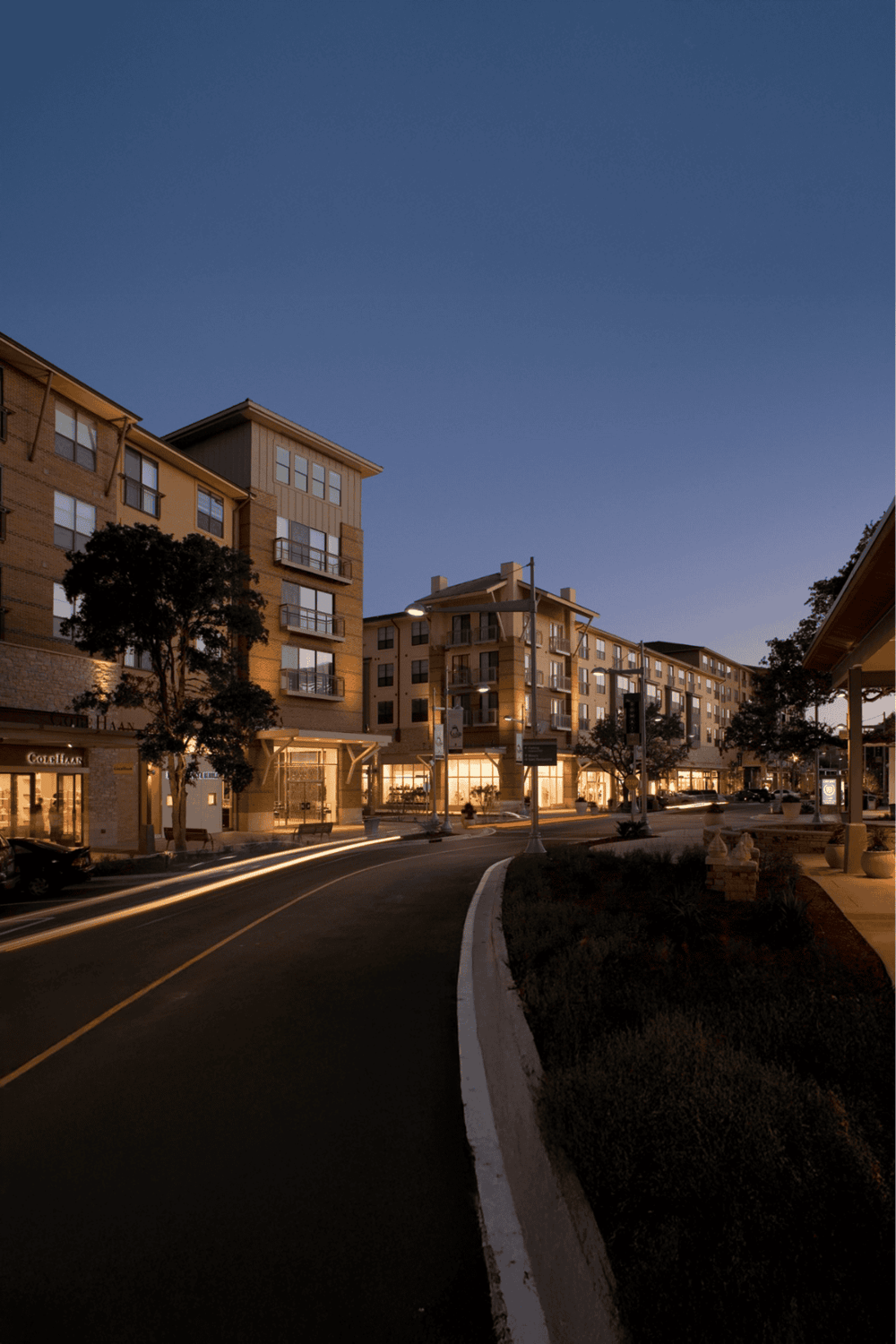 Modern apartment complex lit at dusk in a vibrant urban neighborhood.