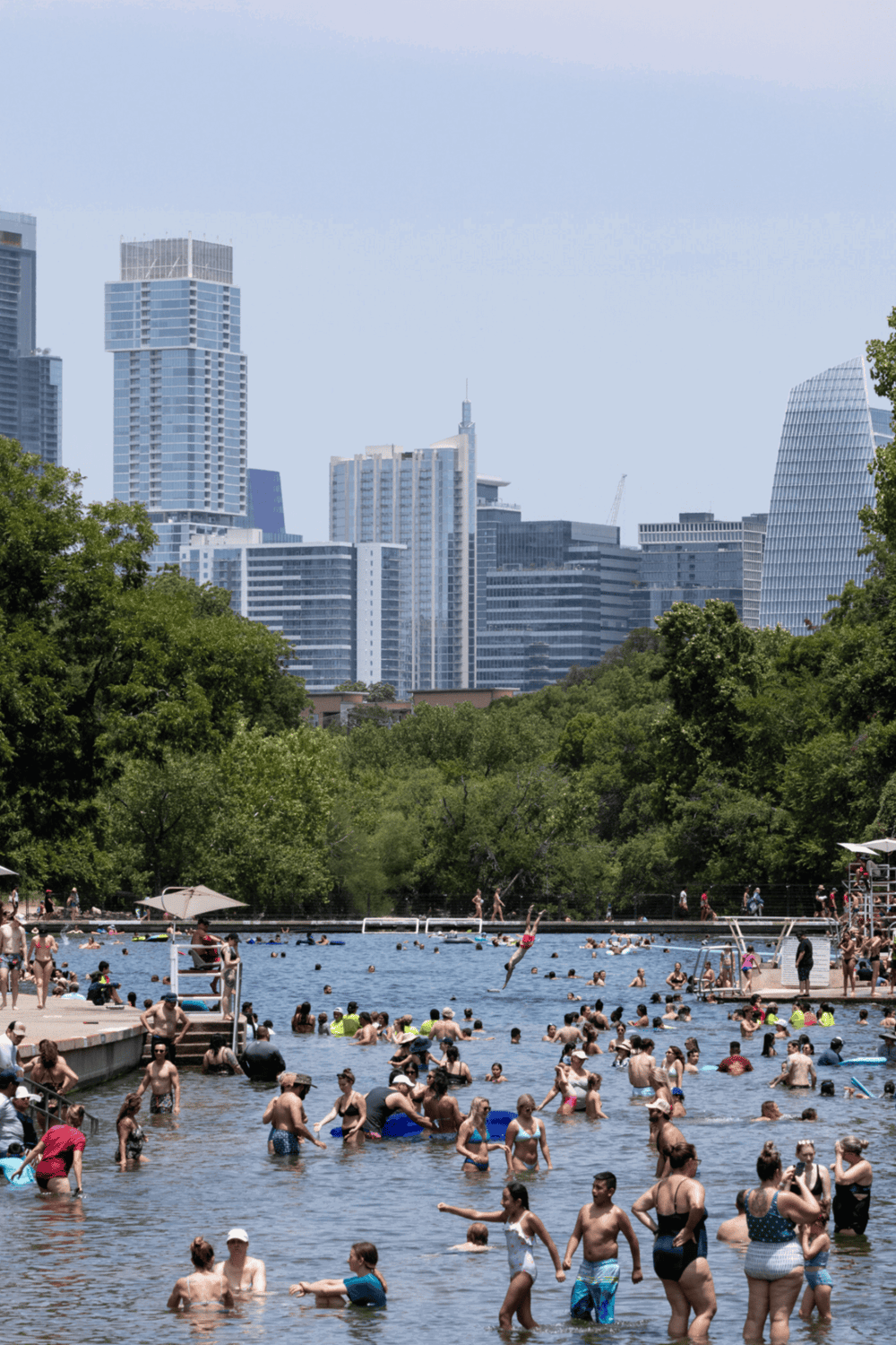 Outdoor city park swimming lake with skyline view, summer activity, families enjoying water, urban oasis, QuestForDirections.