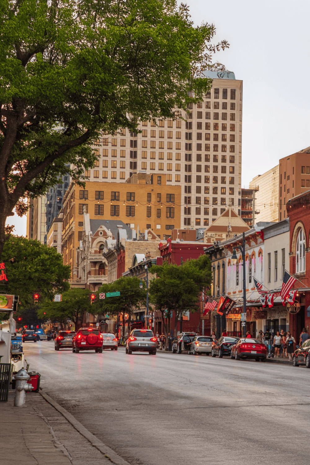 Downtown city street with shops, trees, and tall buildings in the background.