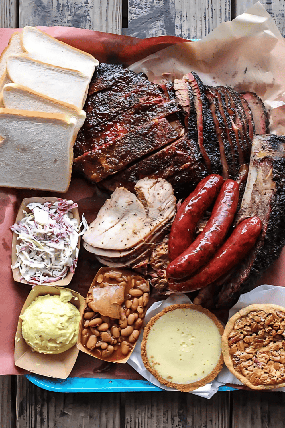 Succulent BBQ platter with smoked brisket, ribs, sausage, coleslaw, baked potato, beans, and pie. Perfect for hearty dining and flavor lovers.