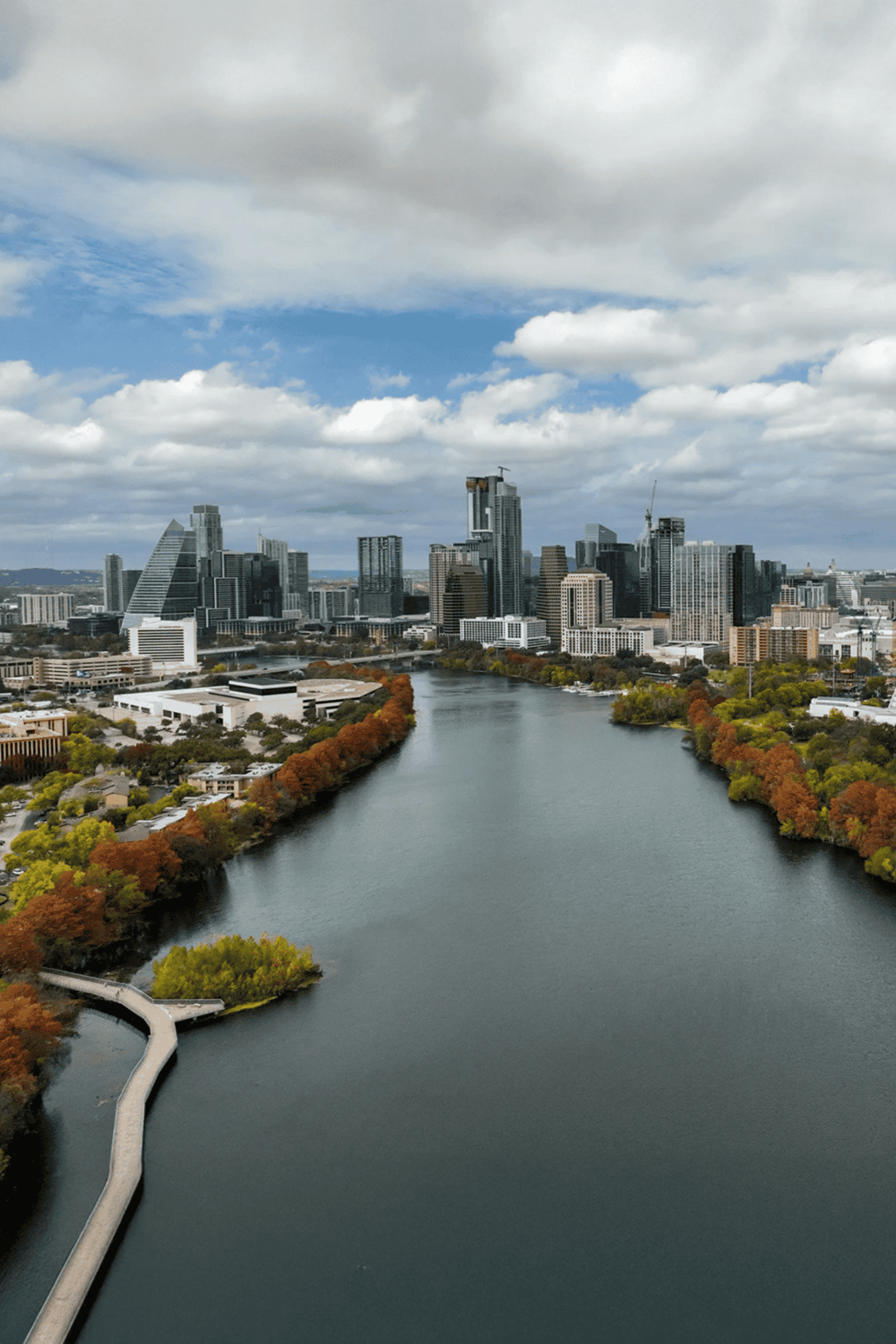 Skyscrapers and river in downtown Austin, Texas during daytime, city skyline with modern buildings and cloudy sky.
