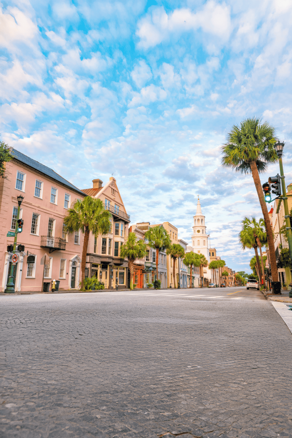Bright colorful historic buildings on a quiet city street with palm trees under a partly cloudy sky.