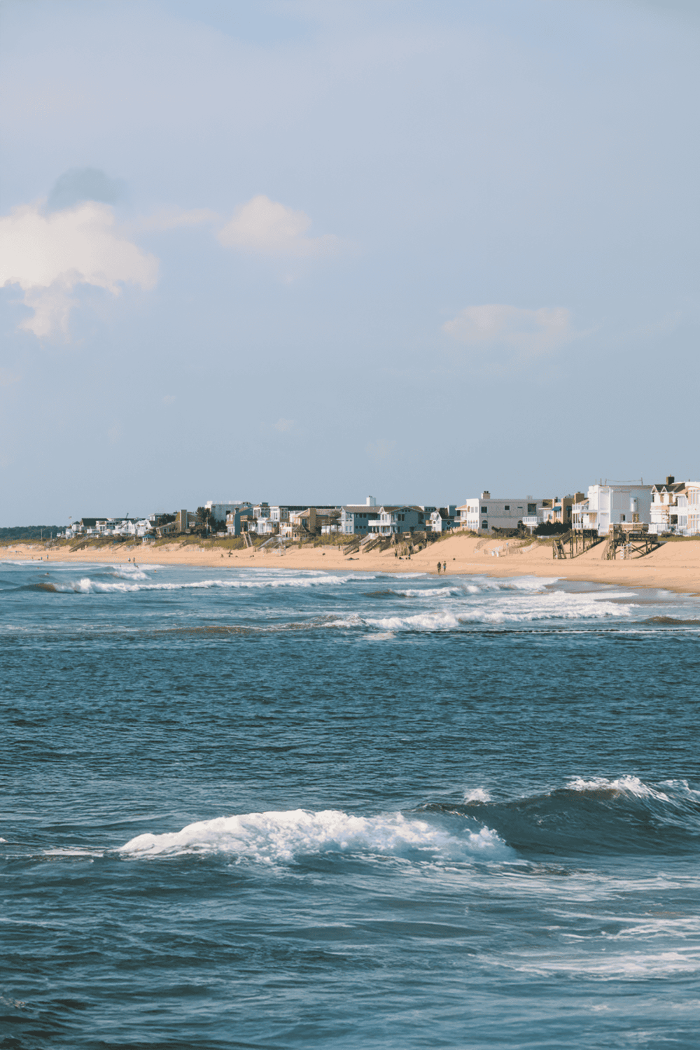Bright beach coastal scene with ocean waves and beachfront houses, perfect for vacation planning and seaside adventures.