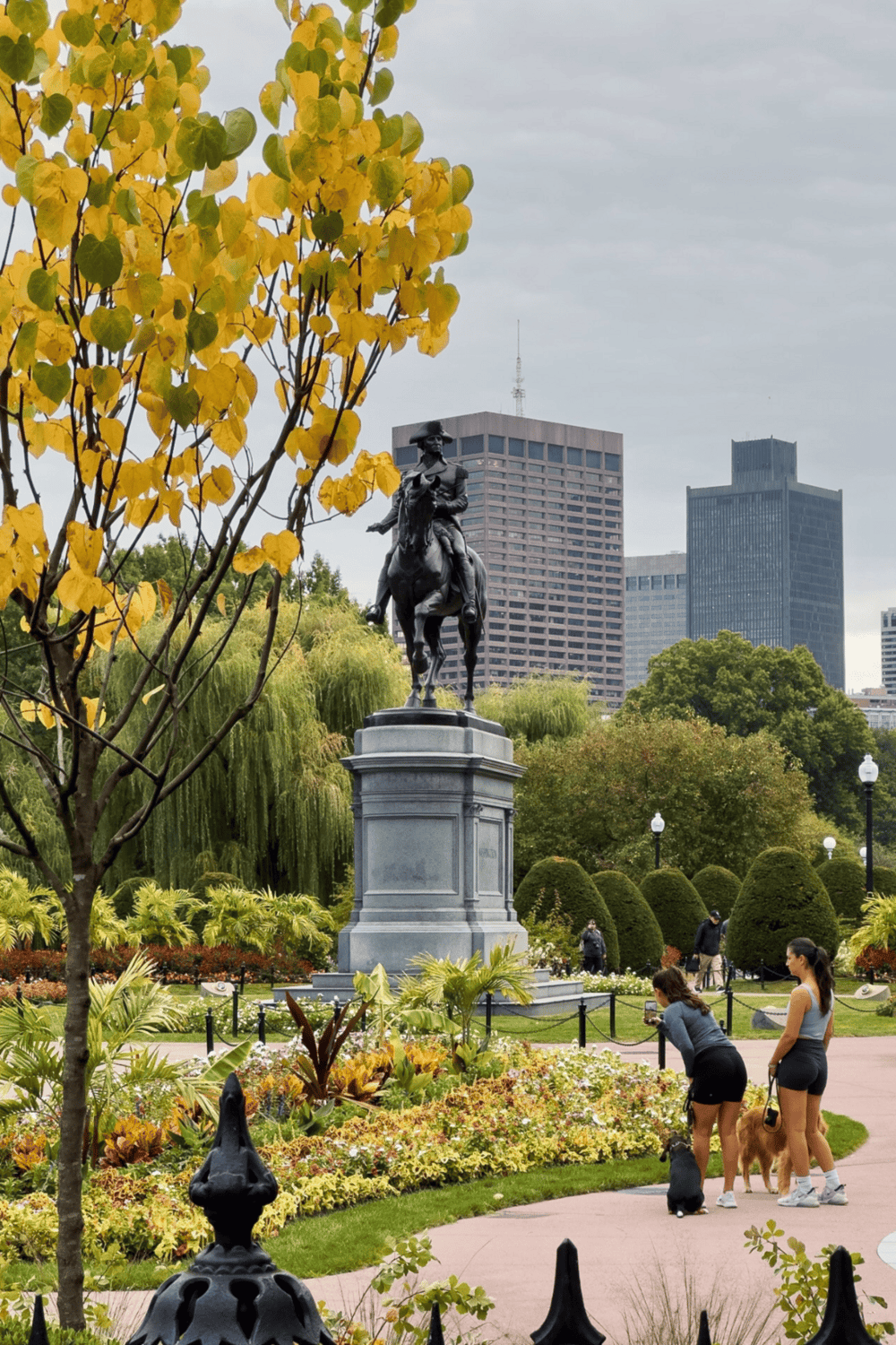 Relaxed city park with statue and skyscrapers, popular destination for sightseeing and outdoor activities.