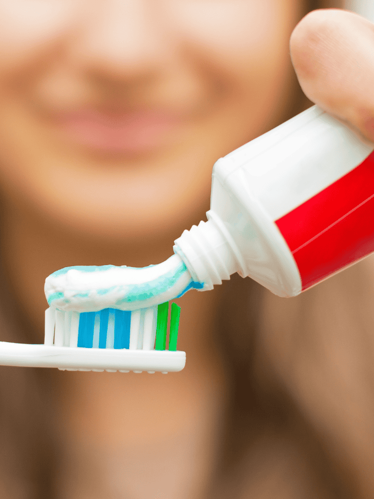 Toothpaste being squeezed onto a toothbrush, close-up shot.