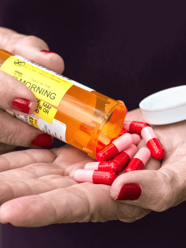 30 mg prescription medication capsules spilled from orange prescription bottle into a person's hand.