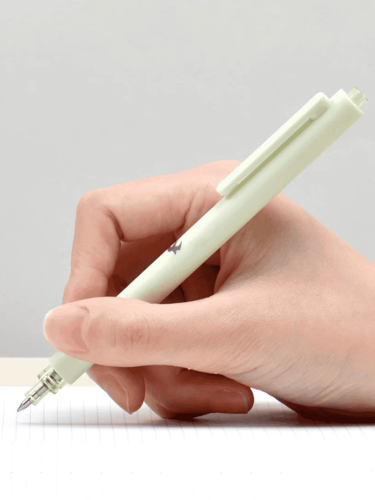 White retractable ballpoint pen in hand writing on lined paper.