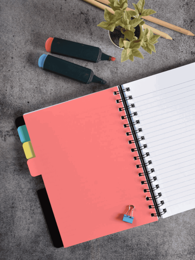Colorful planner with tabs and notebooks on gray surface for organization and planning.