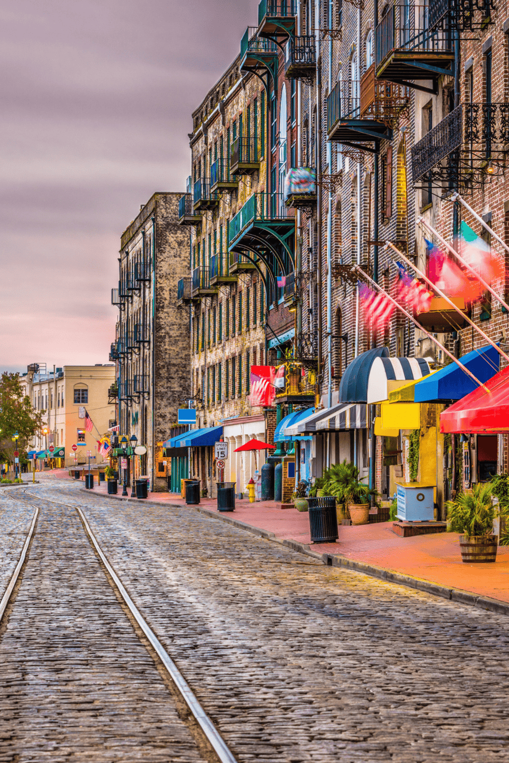 Vibrant historic downtown street with colorful storefronts, cobblestone road, and vintage buildings.