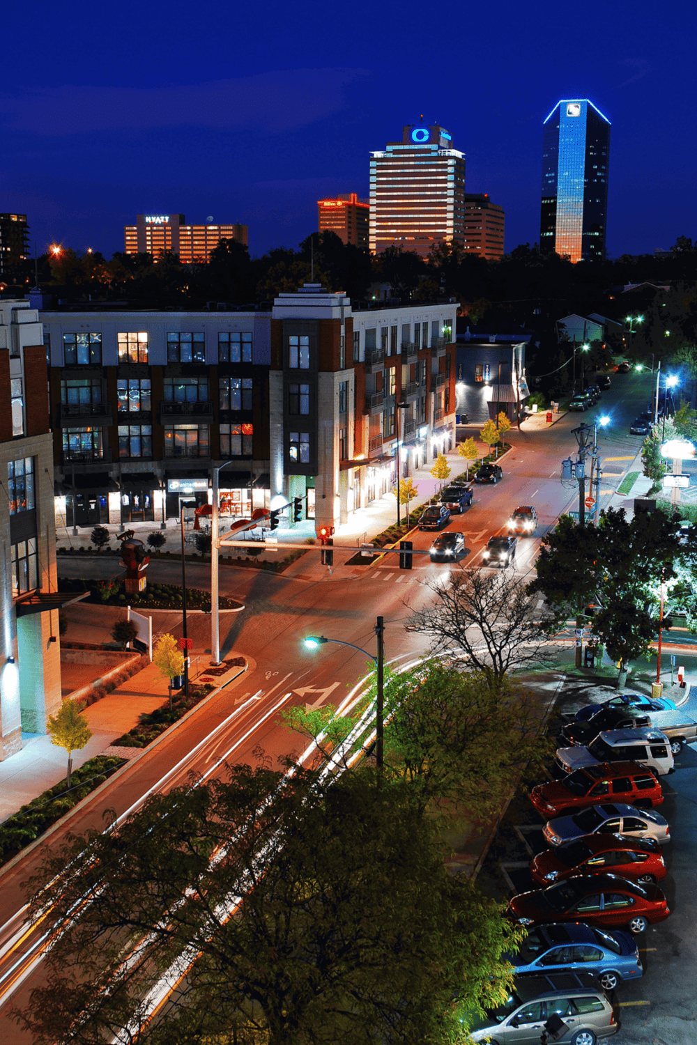 Night cityscape with illuminated buildings, busy street, and vibrant urban atmosphere.