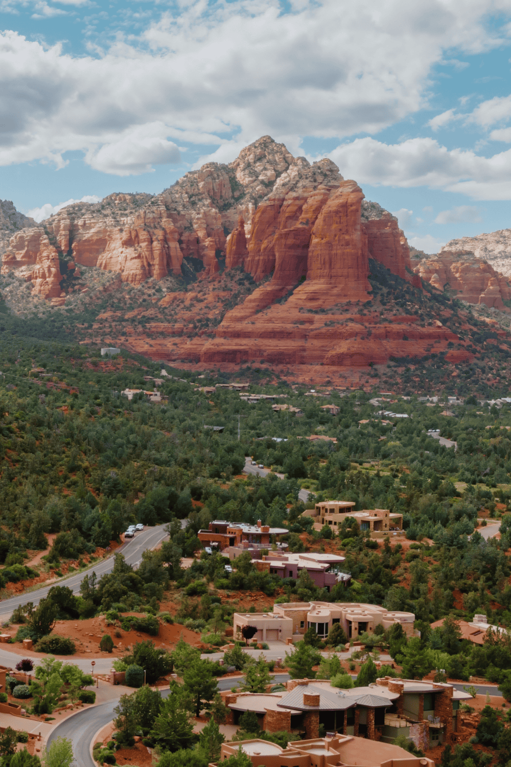 Colorful rock formations in Sedona, Arizona with scenic residential community and lush greenery.