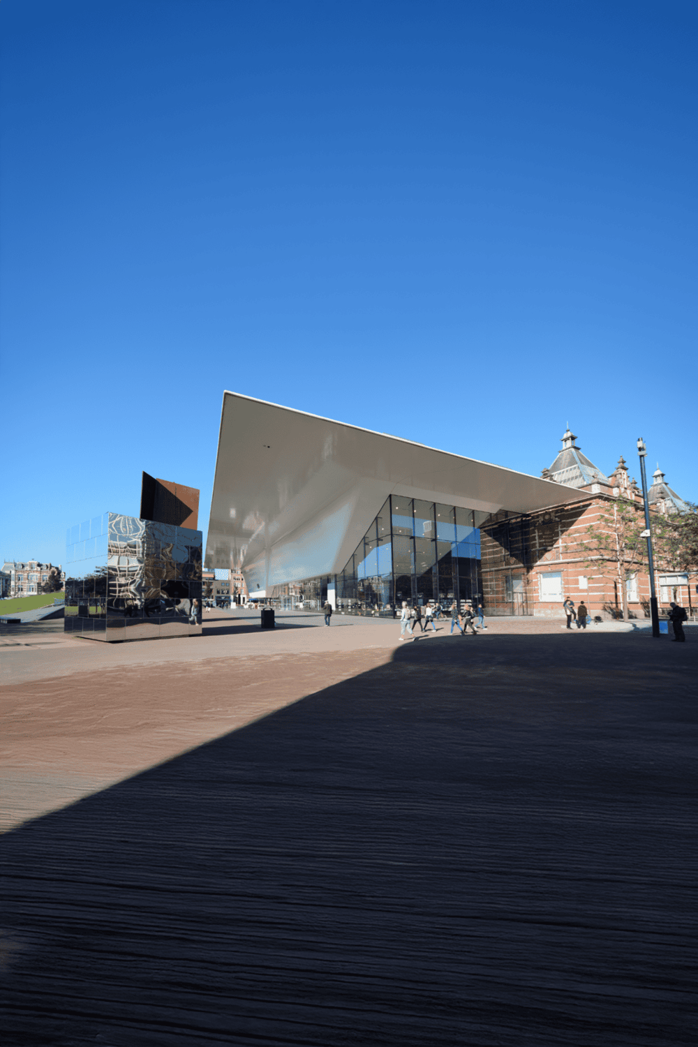 Modern architectural building with glass facade and angular roof under clear blue sky.