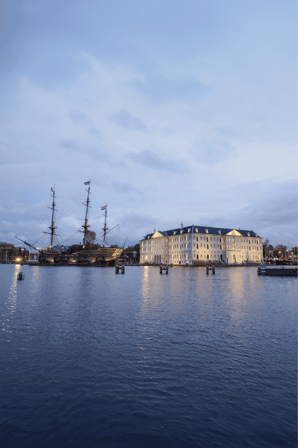 Dockside historic ship and elegant waterfront hotel at dusk, scenic view, perfect for travel and tourism.