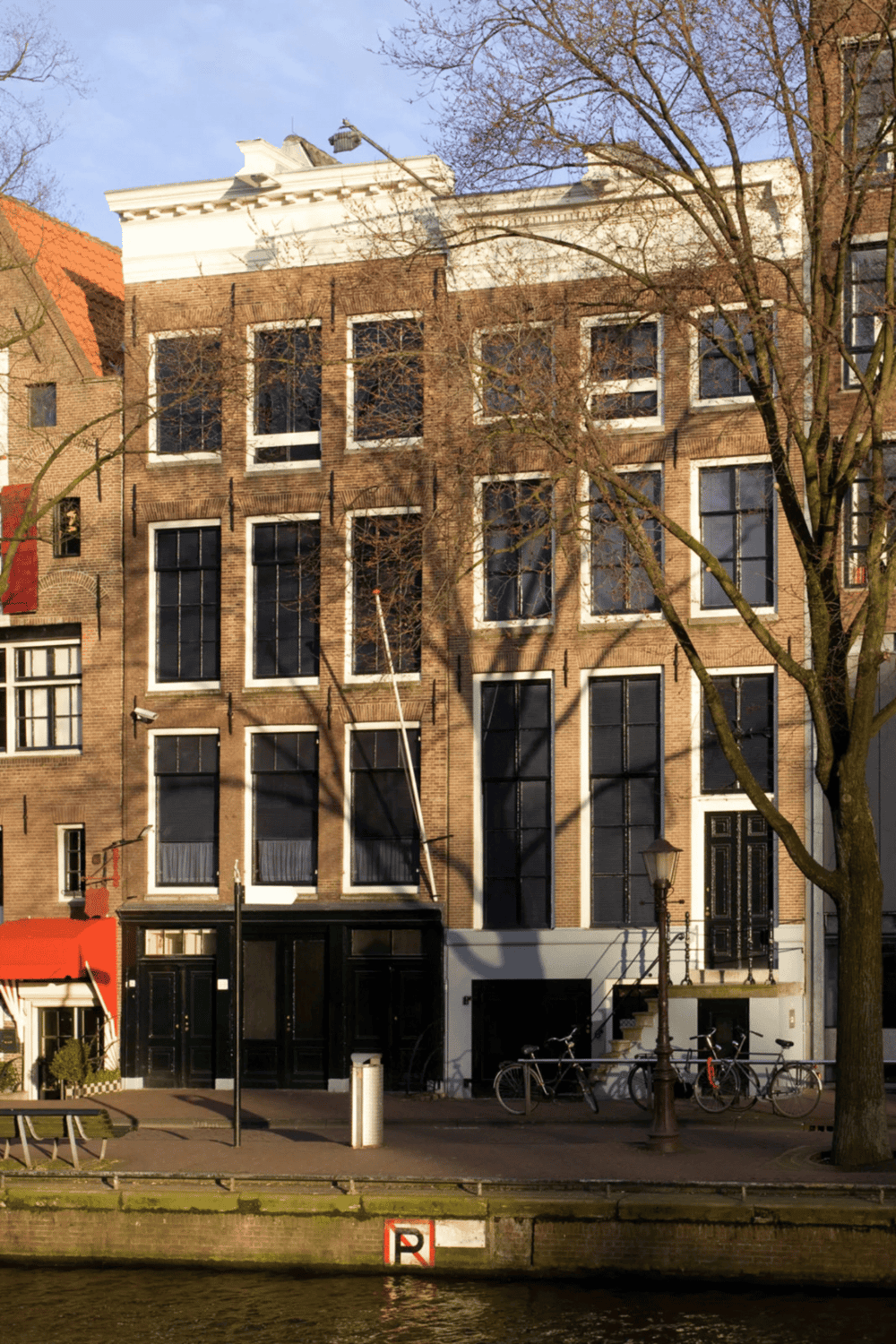 Charming historic building in Amsterdam with large windows and surrounding bicycles.