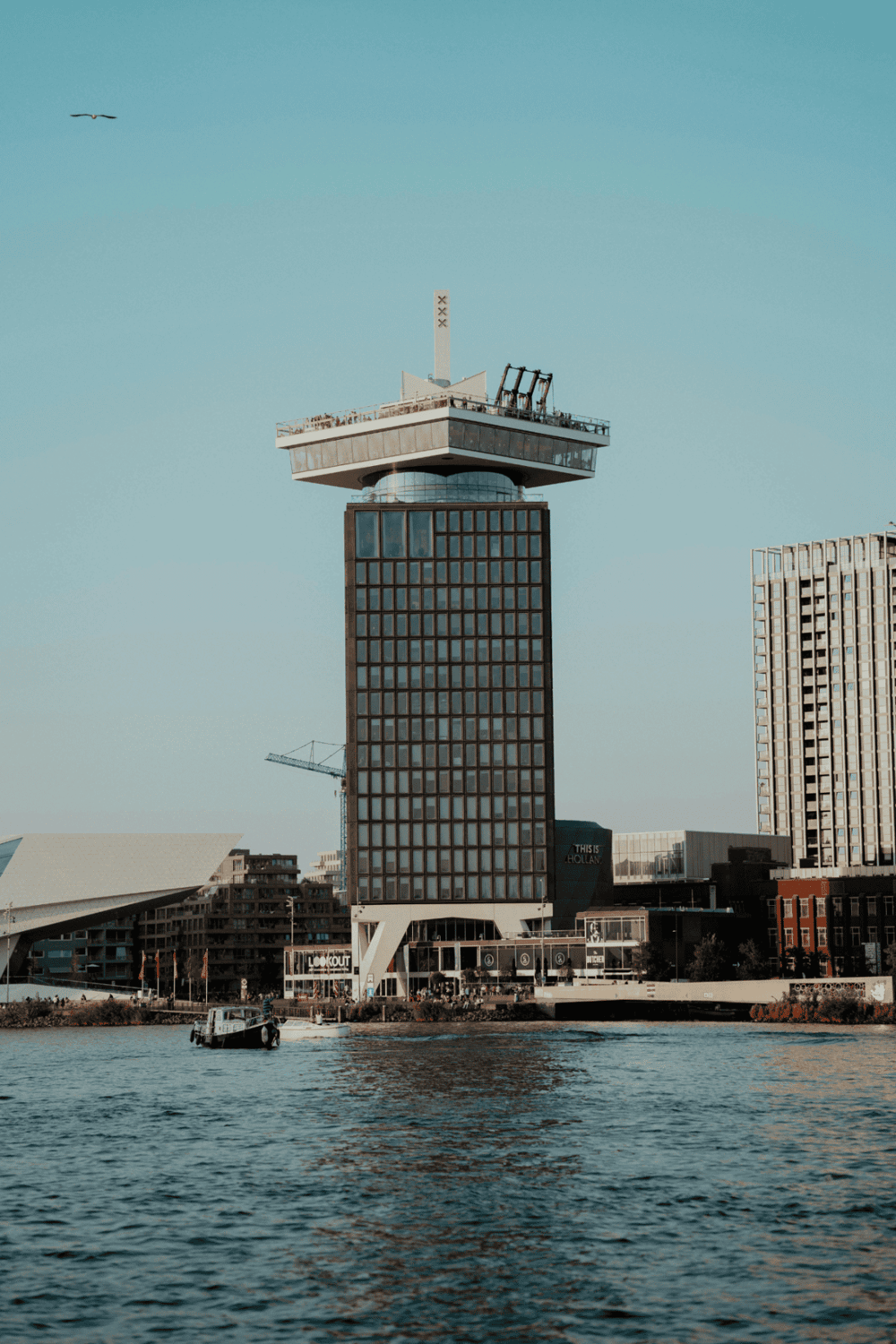 Modern waterfront tower with observation deck and cityscape background.