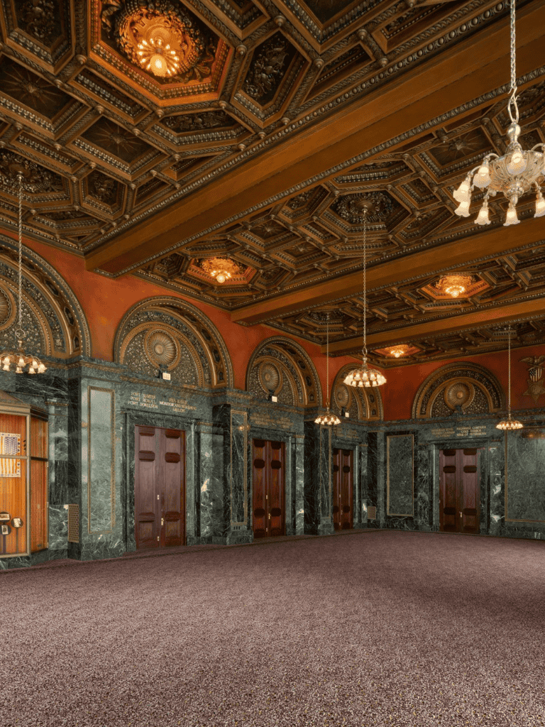 Elegant historic elevator lobby with ornate wood and marble accents, vintage chandeliers, and intricate ceiling design.