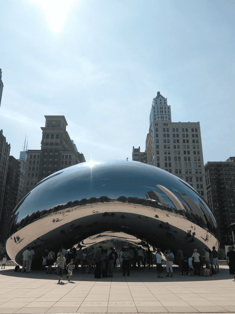 Shiny reflective sculpture at Millennium Park with city skyline, Chicago, Illinois.
