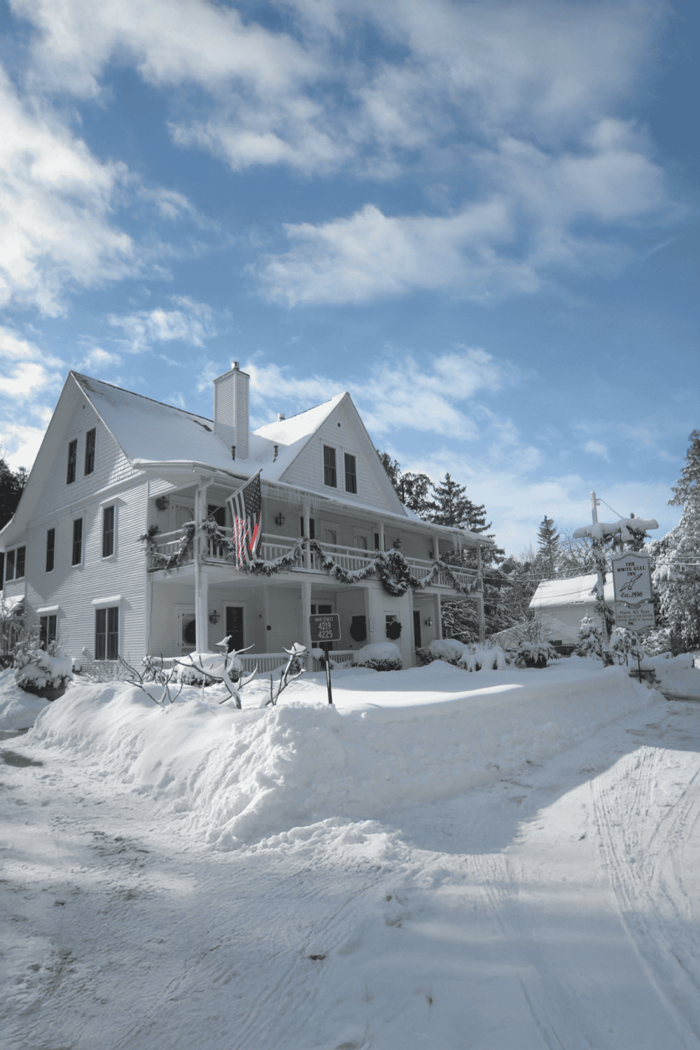 Cozy winter inn decorated for holidays with snow-covered landscape and a bright blue sky.