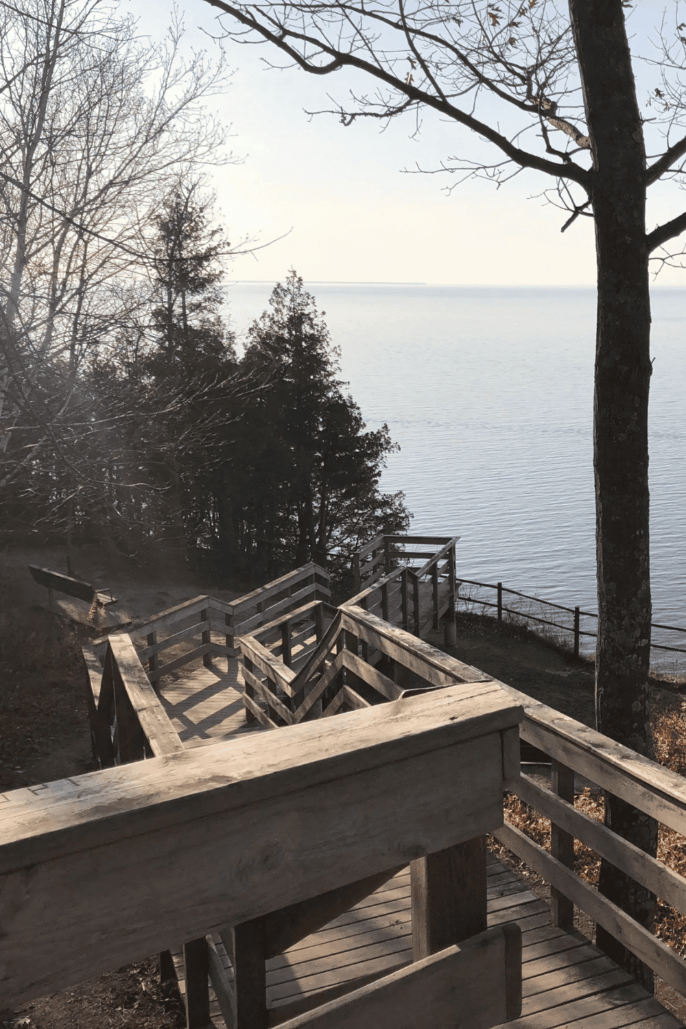 1. Wooden stairs leading to a serene lake view with trees and calm water in the background.