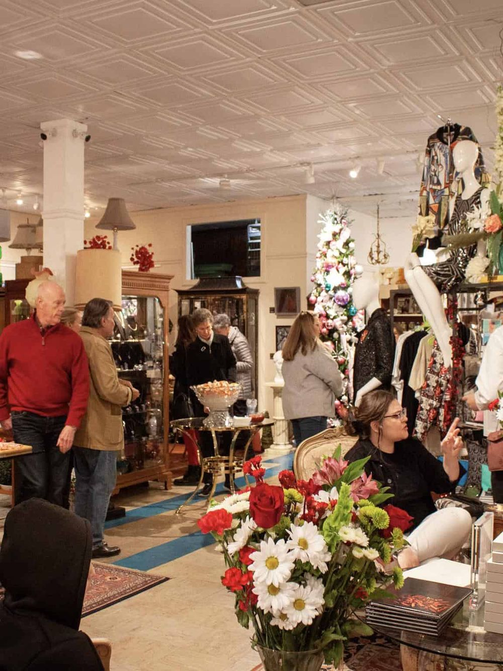 Cozy vintage boutique with shoppers browsing and a display of Christmas decorations.