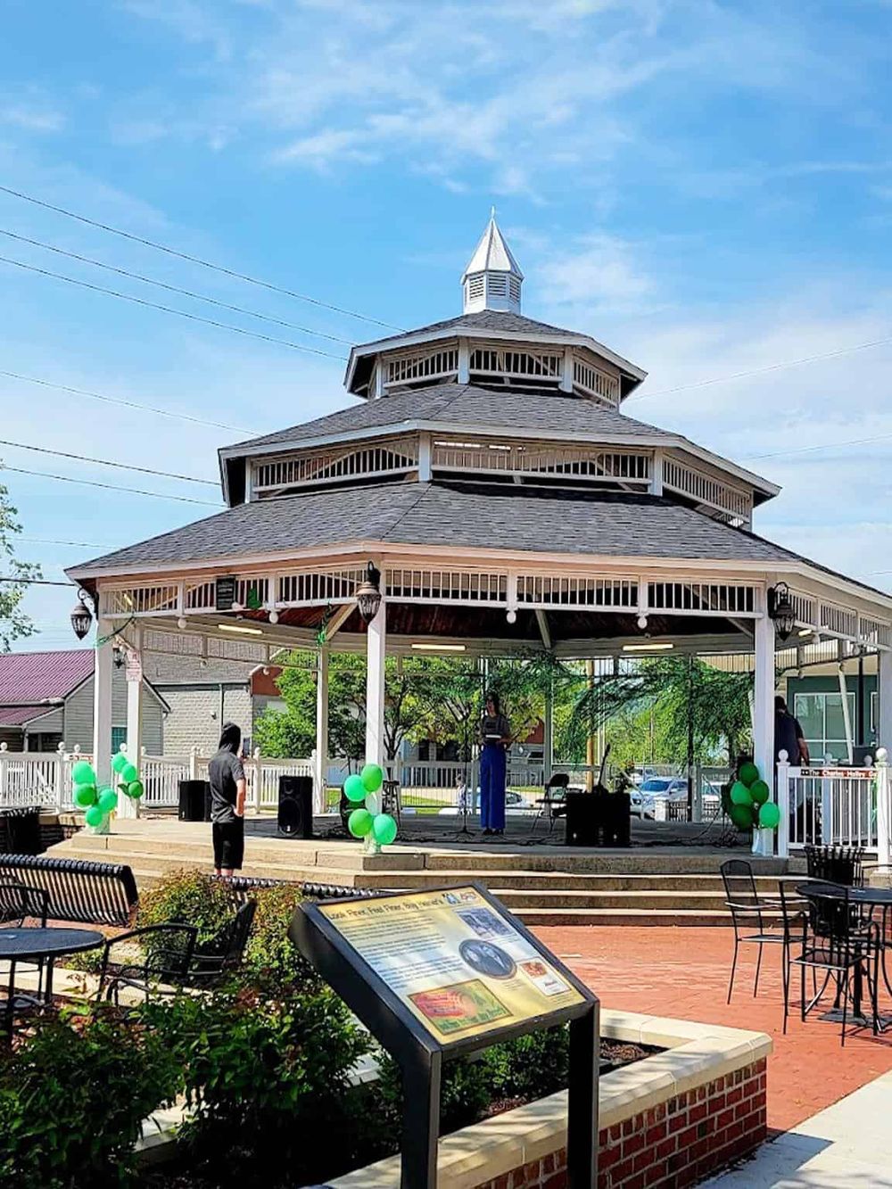 Historic bandstand in downtown with a live outdoor performance and green balloon decorations, creating a vibrant community event.