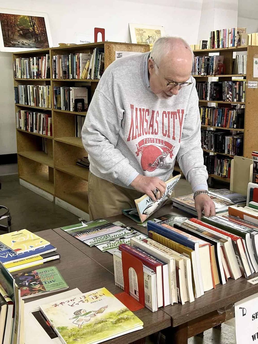 Older man browsing books in a bookstore, exploring various genres for research or leisure.