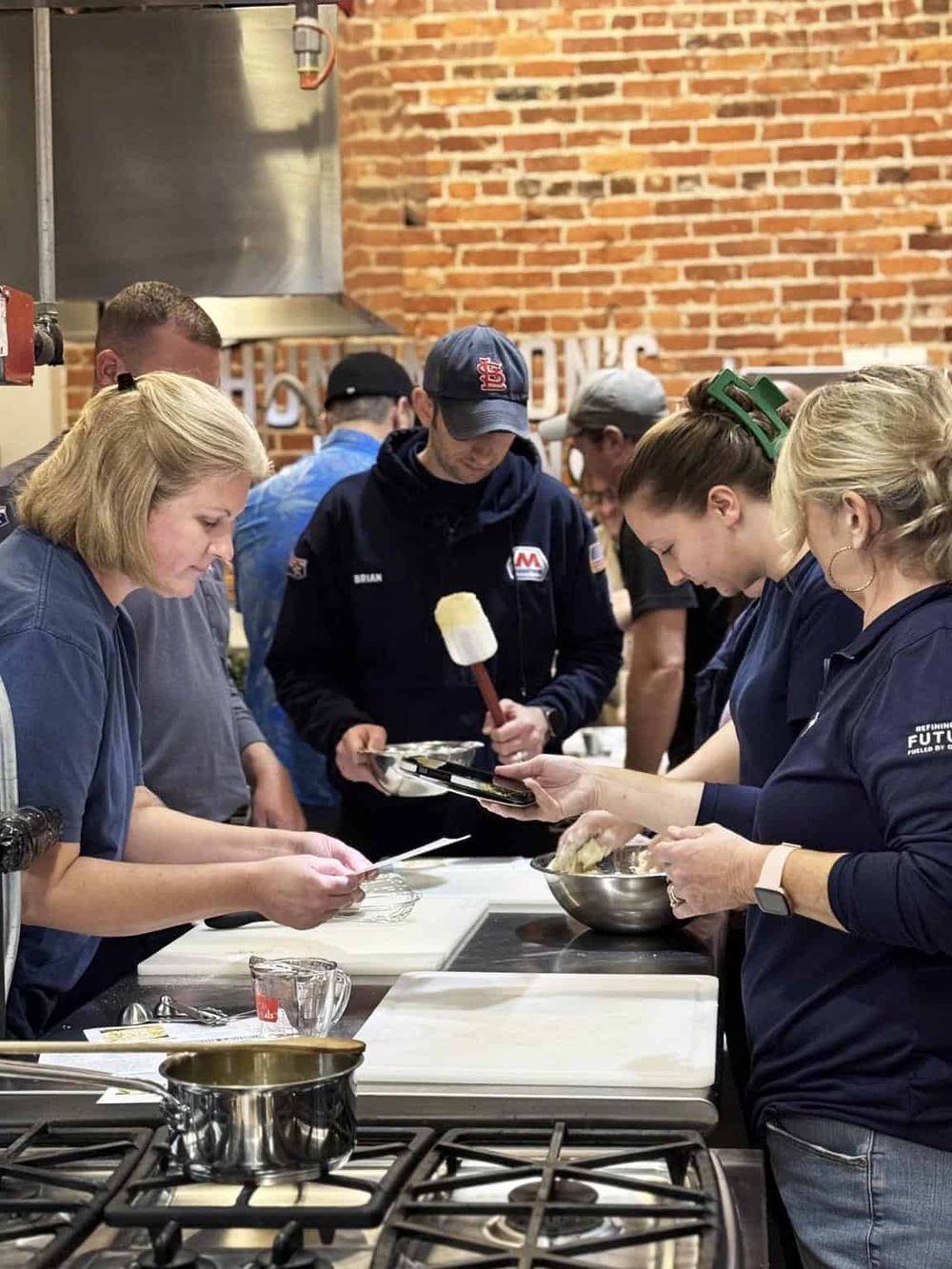 Cooking class with diverse group of people in a modern kitchen, showing teamwork and culinary skills.