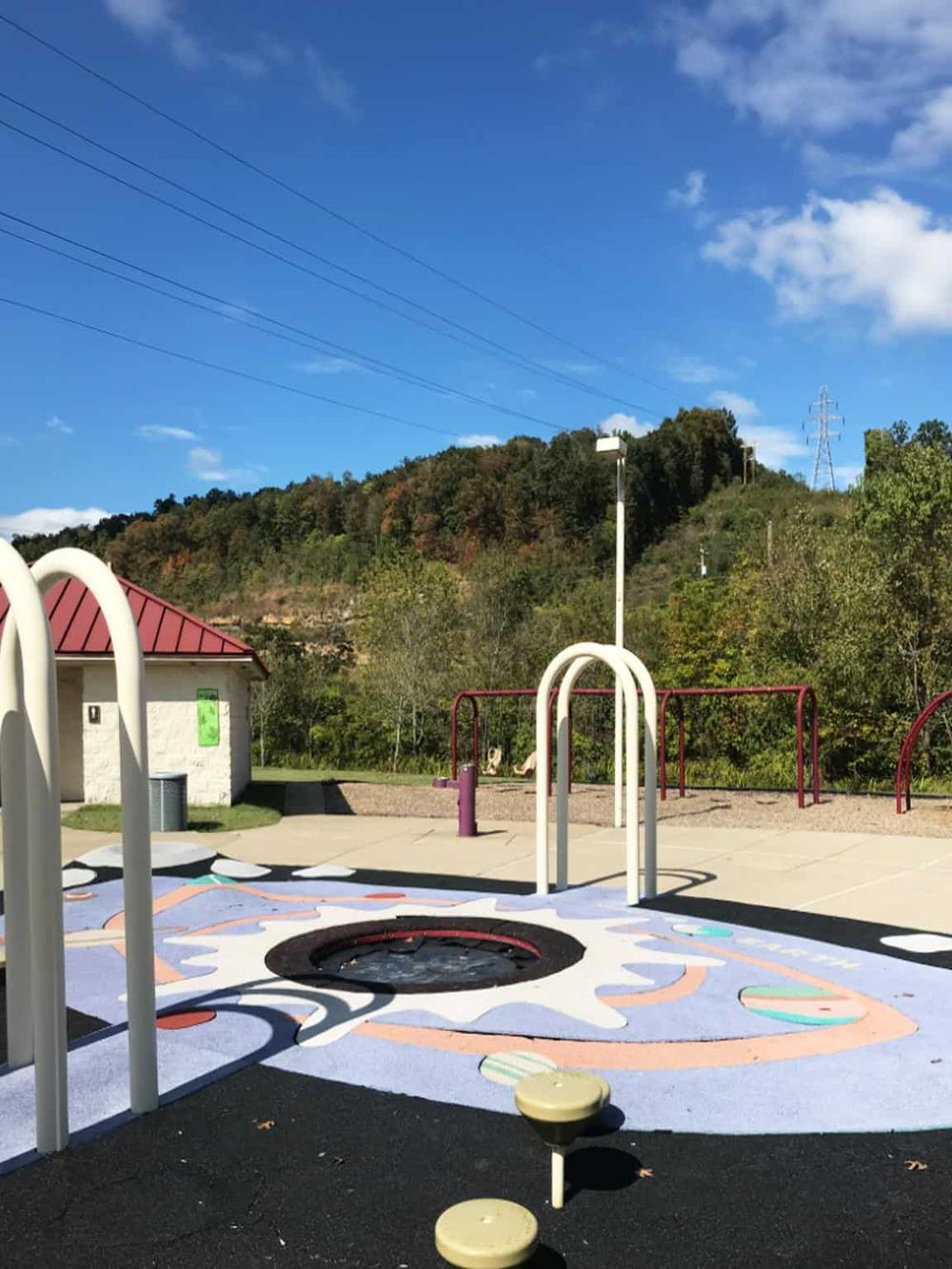 Colorful playground with trampoline and spring riders in a scenic outdoor setting, ideal for children's recreation.
