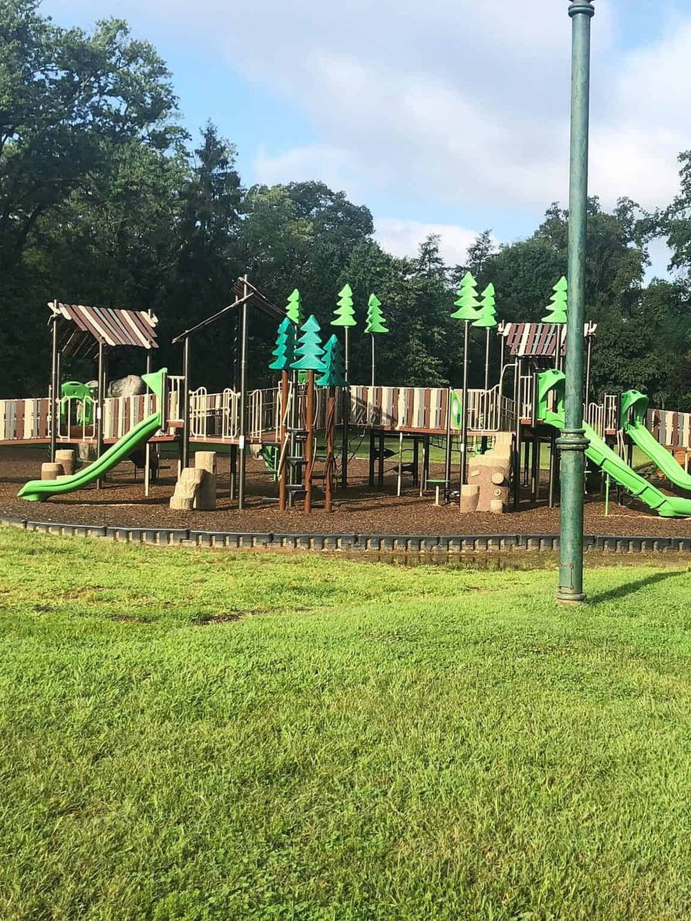 Colorful playground with slides and trees, ideal for outdoor family activities in a park.